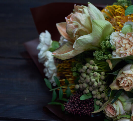 En bukett med olika blommor, inklusive vita och gula blommor, mot en mörk bakgrund.
